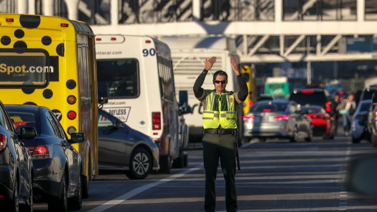 A Los Angeles airport police officer directs traffic at Los Angeles International Airport on Nov. 22, the day before Thanksgiving. The airport ranked in the middle in parking expenses among major U.S. airports, according to a new study.