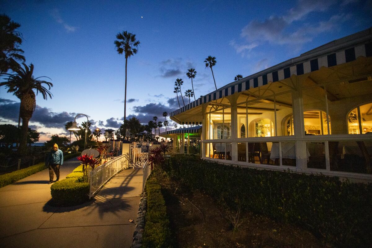 A man walks past Las Brisas in Laguna Beach at dusk on March 18.