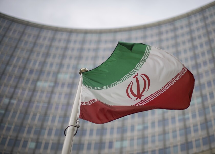 A national flag of Iran waves in front of the building of the International Atomic Energy Agency, IAEA, in Vienna, Austria, Friday, Dec. 17, 2021. (AP Photo/Michael Gruber)