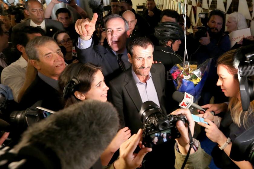 Ali Vayeghan, center, an Iranian citizen with a valid U.S. visa, is swarmed by the media as he is escorted through LAX by L.A. Mayor Eric Garcetti after his arrival.