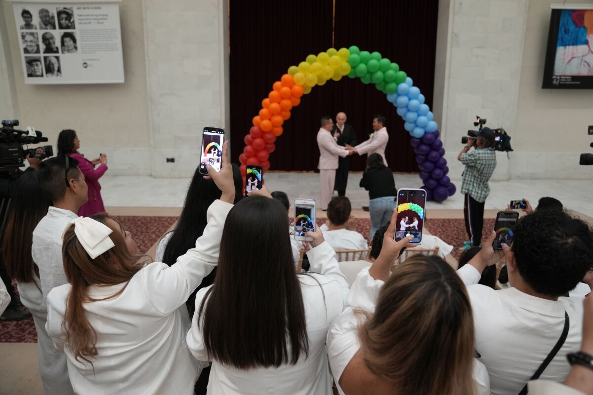 People record the wedding of Andy Correa, center left, and Panchanit Wongsrila at City Hall in San Francisco