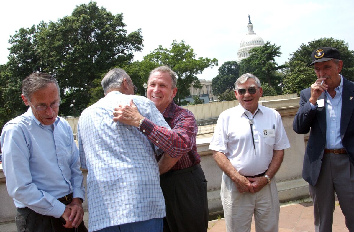 FILE - Edward Shames, center, hugs Ed McClung, center left, both members of the World War II Army Company E of the 506th Regiment of the 101st Airborne, with veterans Jack Foley, left, Joe Lesniewski, right, and Shifty Powers, far right, at the Library of Congress in Washington, on July 16, 2003. Shames, who was the last surviving officer of “Easy Company,” which inspired the HBO miniseries and book “Band of Brothers,” has died at age 99. An obituary posted by the Holomon-Brown Funeral Home & Crematory said Shames, of Norfolk, Va., died peacefully at his home on Friday, Dec. 3, 2021. (AP Photo/Gerald Herbert, File)