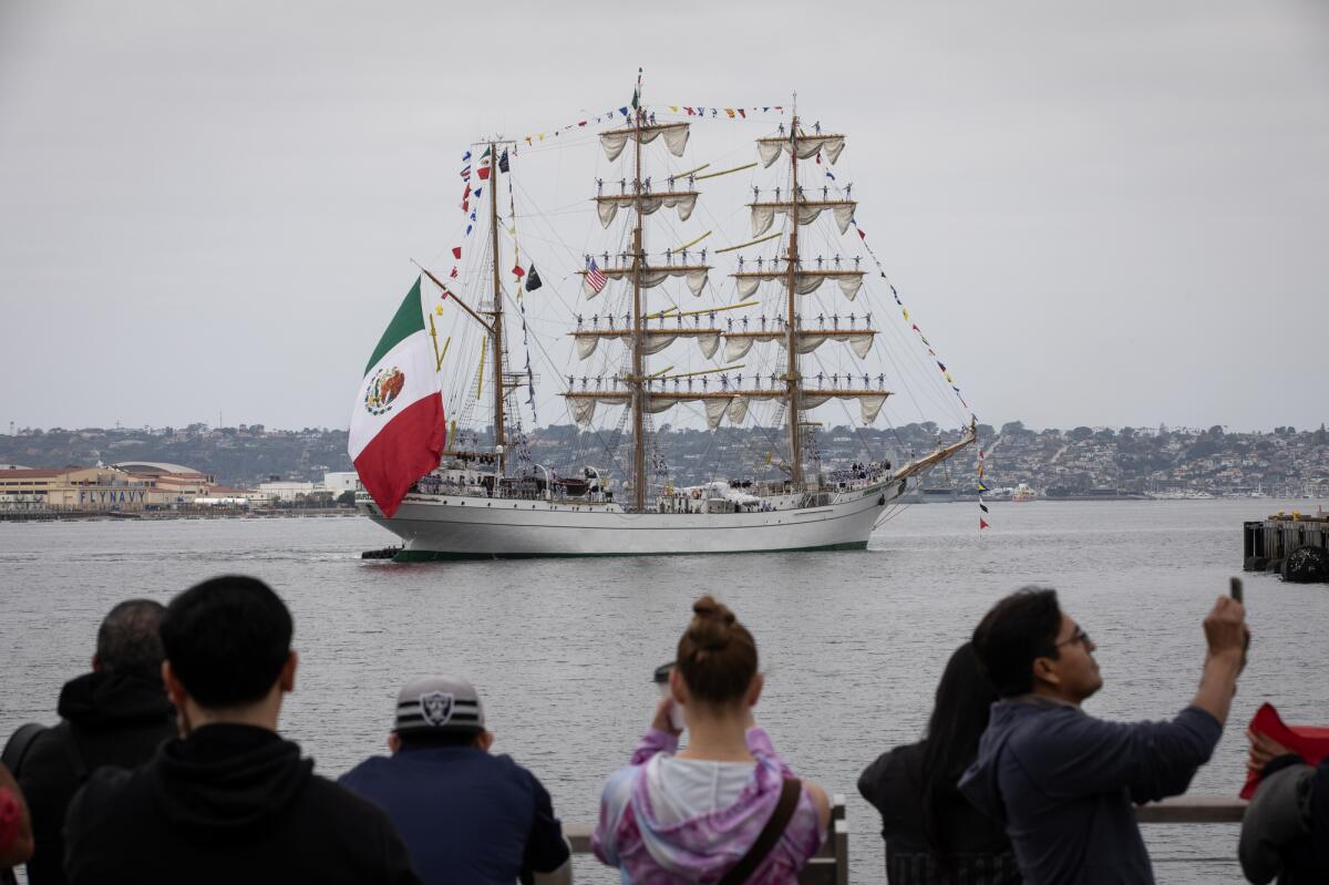 Dozens of people cheer as a 261-person crew arrives on the tall ship Cuauhtemoc