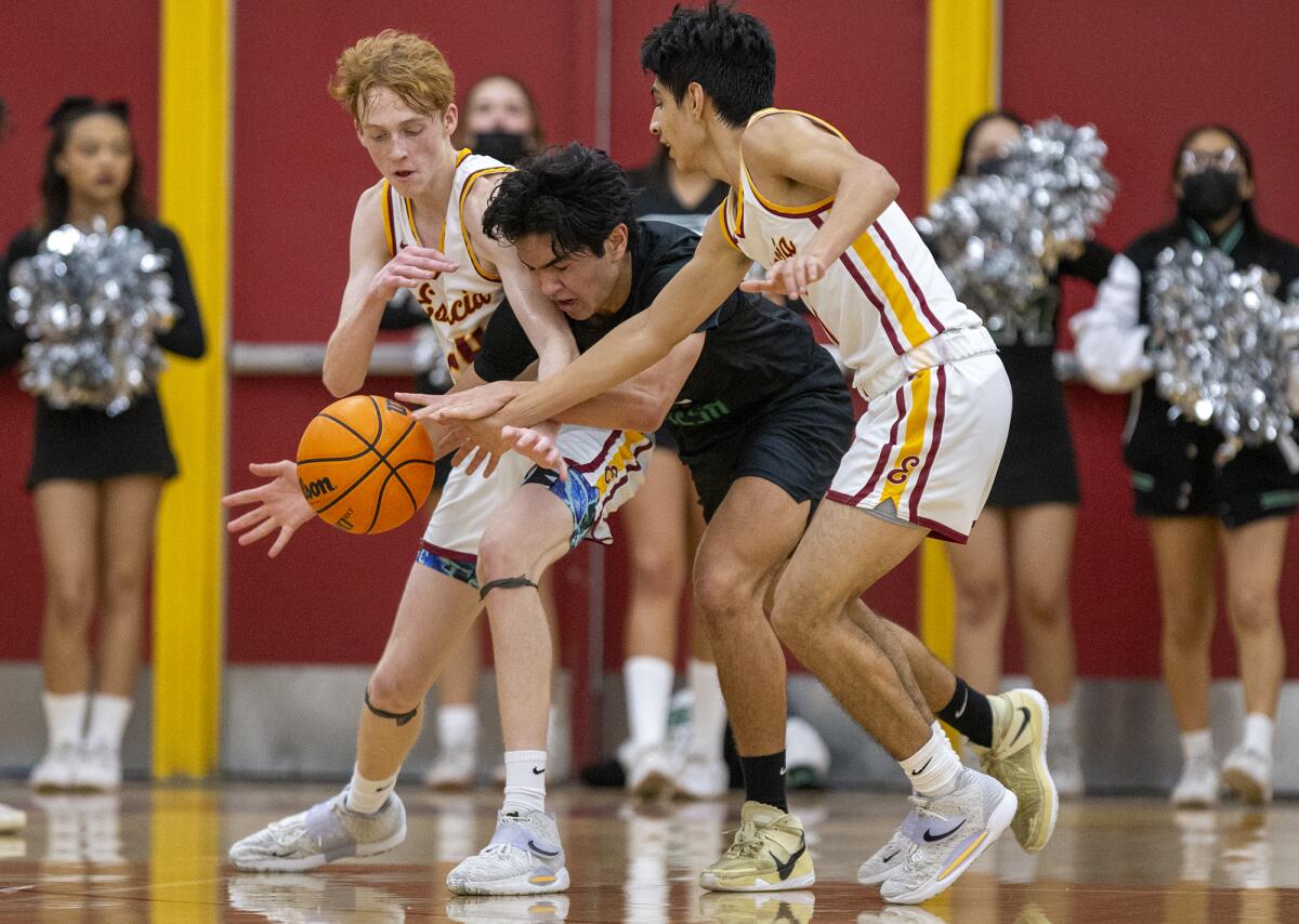 Estancia's Reef Johnson, left, and Juan Padilla, right, battle for a loose ball against Costa Mesa's Aiden Spallone.