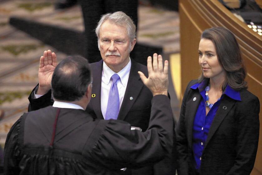 Oregon Gov. John Kitzhaber is sworn in Jan. 12 with First Lady Cylvia Hayes at his side. Friday, he announced he would step down amid allegations that Hayes sought to improperly influence him.
