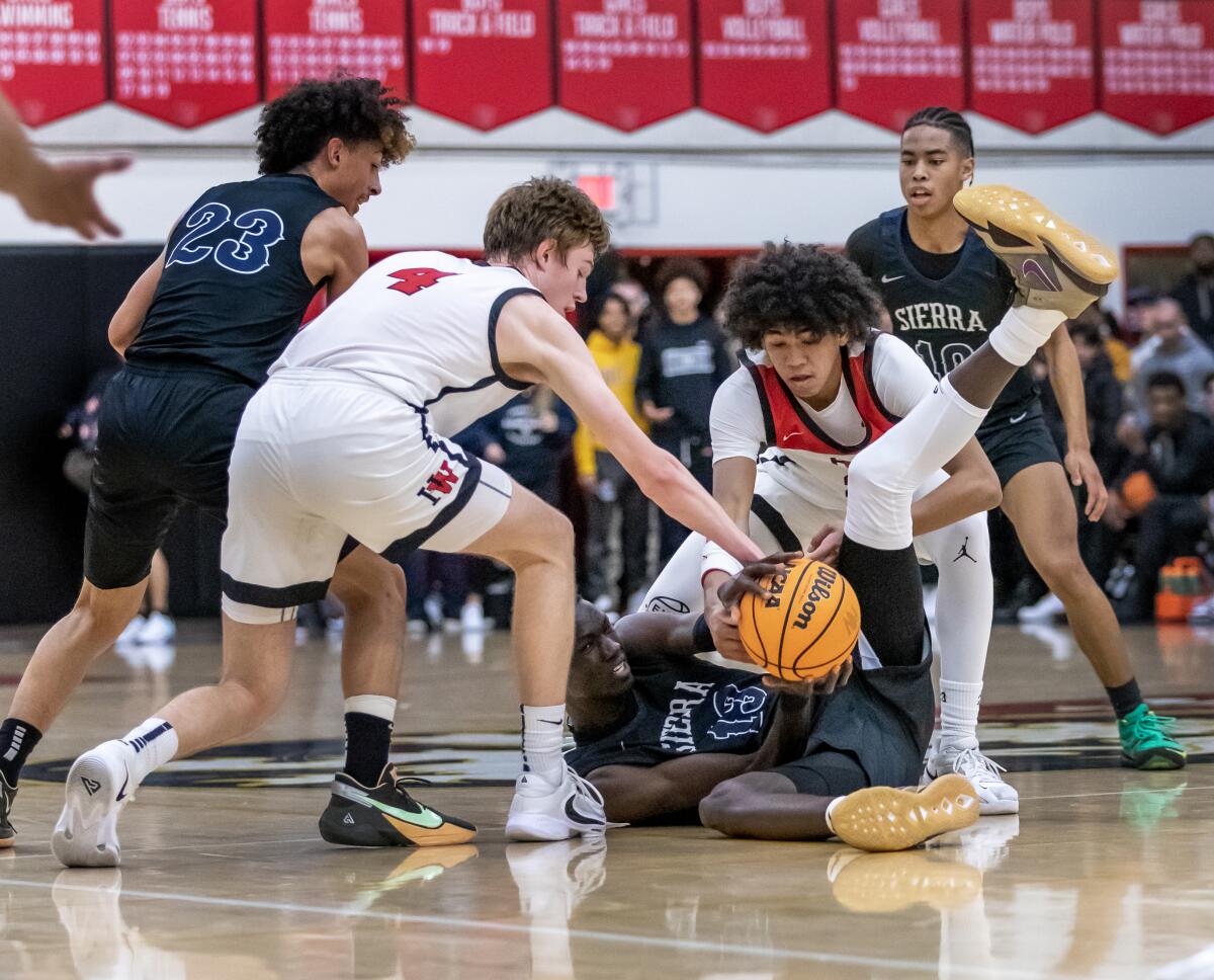 Sierra Canyon's Majok Chuol (13, on floor) battles Harvard-Westlake's Nikolas Khamenia (4) and Christian Horry (15).