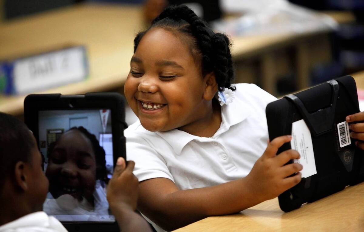 L.A. Unified has begun providing iPads to students in hopes of boosting achievement. Above, Avery Sheppard, left, views a smiling Tiannah Dizadare on his L.A. Unified-provided iPad in their classroom at Broadacres Avenue Elementary in Carson.