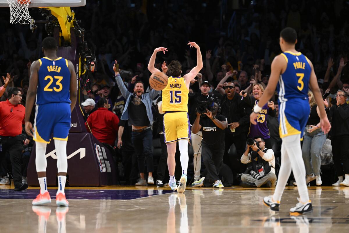 Lakers guard Austin Reaves walks toward the baseline seats while celebrating after making a half-court shot before halftime.