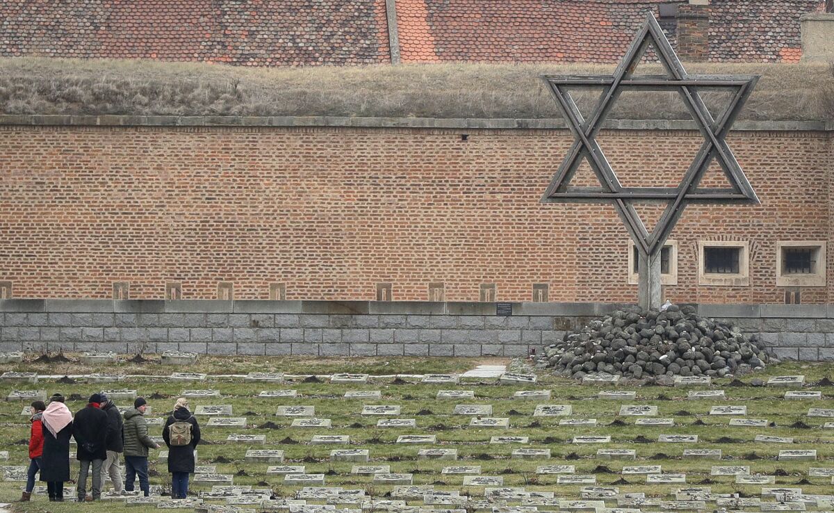 In this Thursday Jan. 24, 2019 file photo visitors walk through the cemetery of the former Nazi concentration camp in Terezin, Czech Republic. The antisemitic incidents in the Czech Republic continued to rise last year, the Jewish community said Wednesday June 9, 2021. In its annual report, the Federation of the Jewish Communities said it registered 874 antisemitic attacks in 2020, 180 more than the previous year. (AP Photo/Petr David Josek, file)