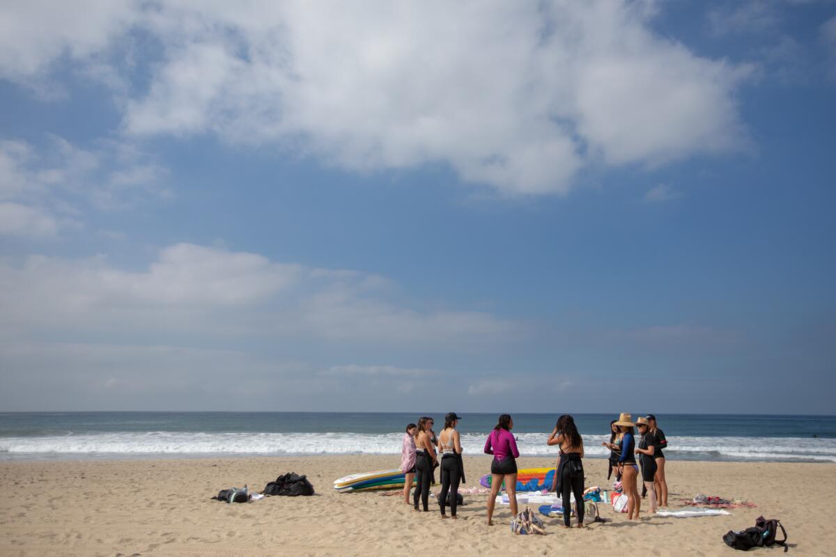 A group of women stand together in a circle on the beach in Santa Monica.