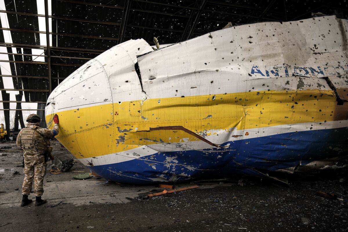 A Ukrainian serviceman touches the nose of the Antonov An-225  aircraft destroyed during fighting