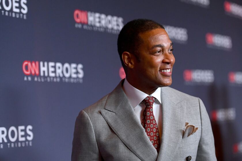 man, don lemon, smiling on red carpet in gray suit and red tie, turning his head away from camera, toward crowd
