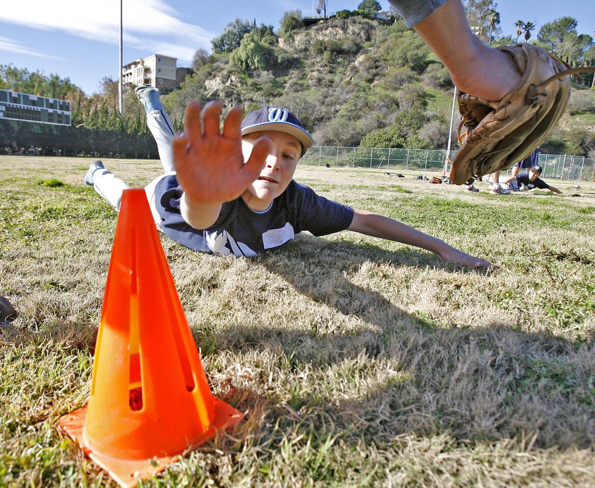 Troy Leef, 13, of La Crescenta, reaches for a cone that is a base he is reaching for during a sliding drill at the Annual Falcon Baseball Camp at Stengel Field in Glendale on Thursday, December 27, 2012.