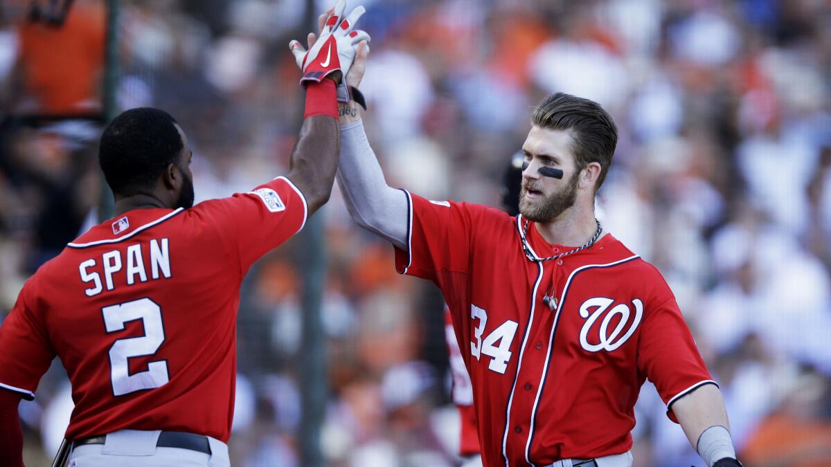 Washington Nationals teammates Denard Span, left, and Bryce Harper celebrate after scoring on a throwing error during the seventh inning of a 4-1 win over the San Francisco Giants in Game 3 of the National League division series Monday.