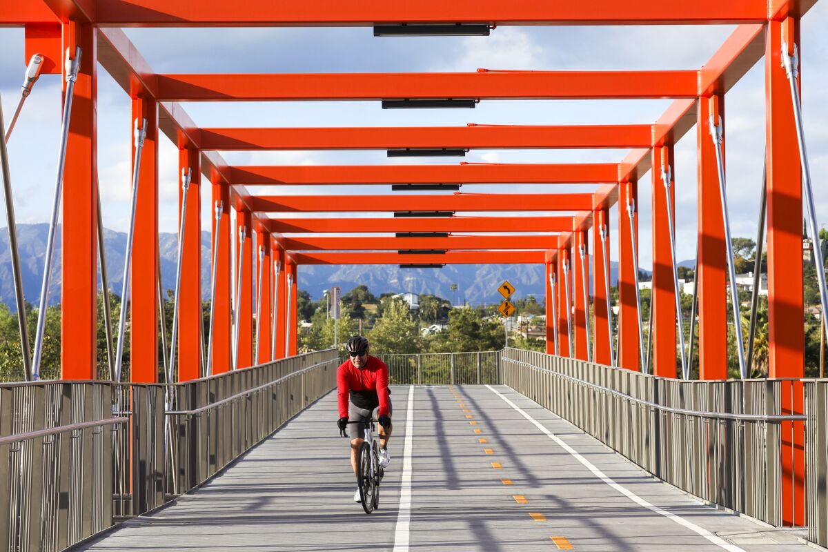 A man rides his bike across the new, bright orange Taylor Yard Bridge.