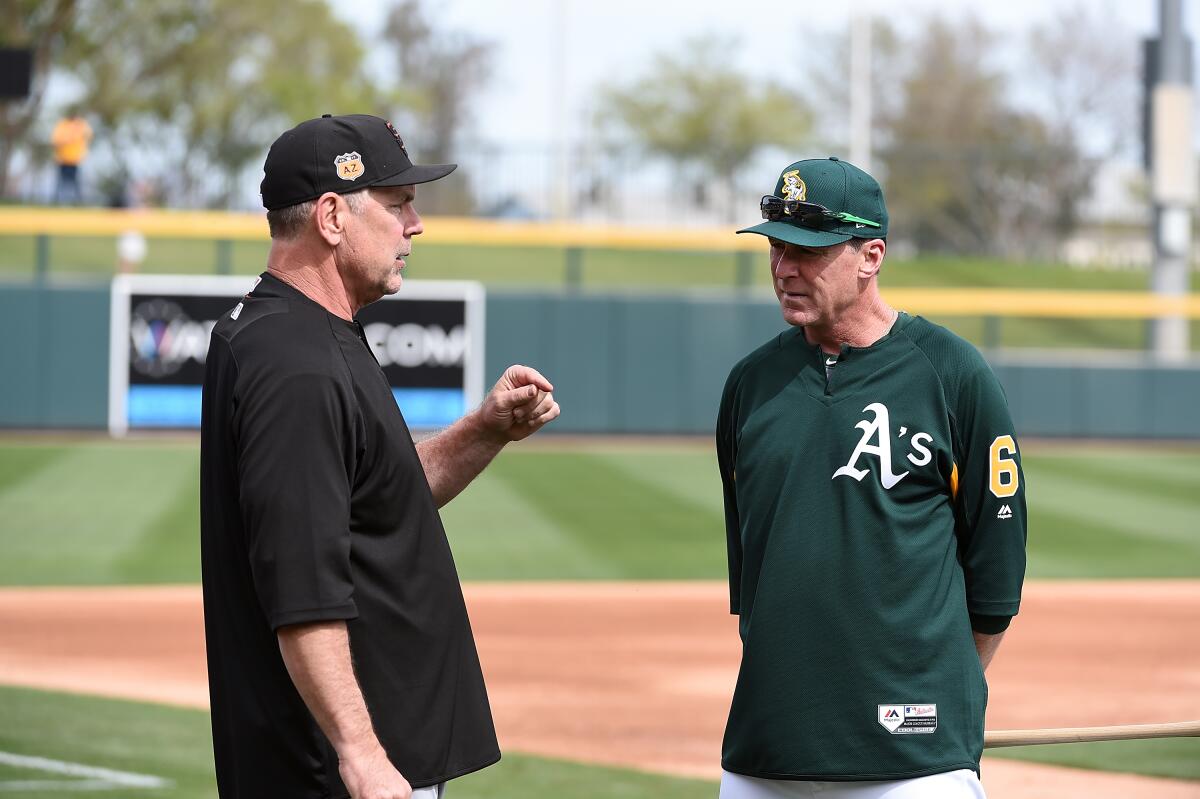 Managers Bruce Bochy (left) and Bob Melvin talk before spring training game in 2017 in Mesa, Ariz.