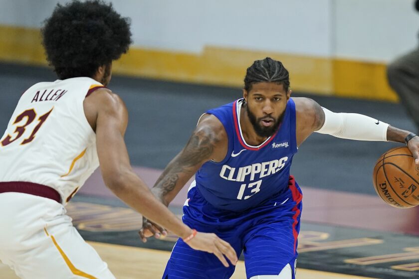 Los Angeles Clippers' Paul George, right, drives to the basket against Cleveland Cavaliers' Jarrett Allen in the second half of an NBA basketball game, Wednesday, Feb. 3, 2021, in Cleveland. The Clippers won 121-99.(AP Photo/Tony Dejak)