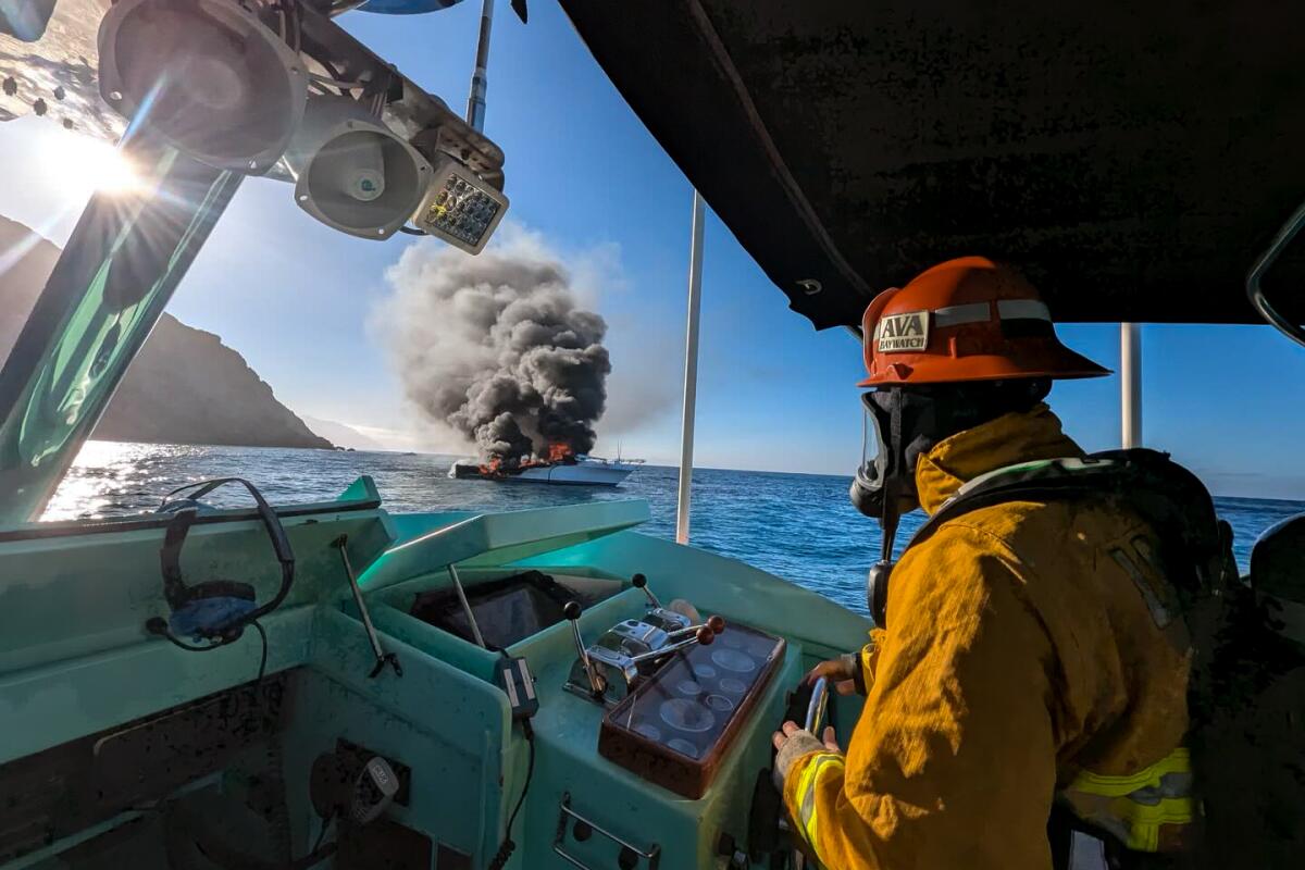 A firefighter looks toward a burning boat.
