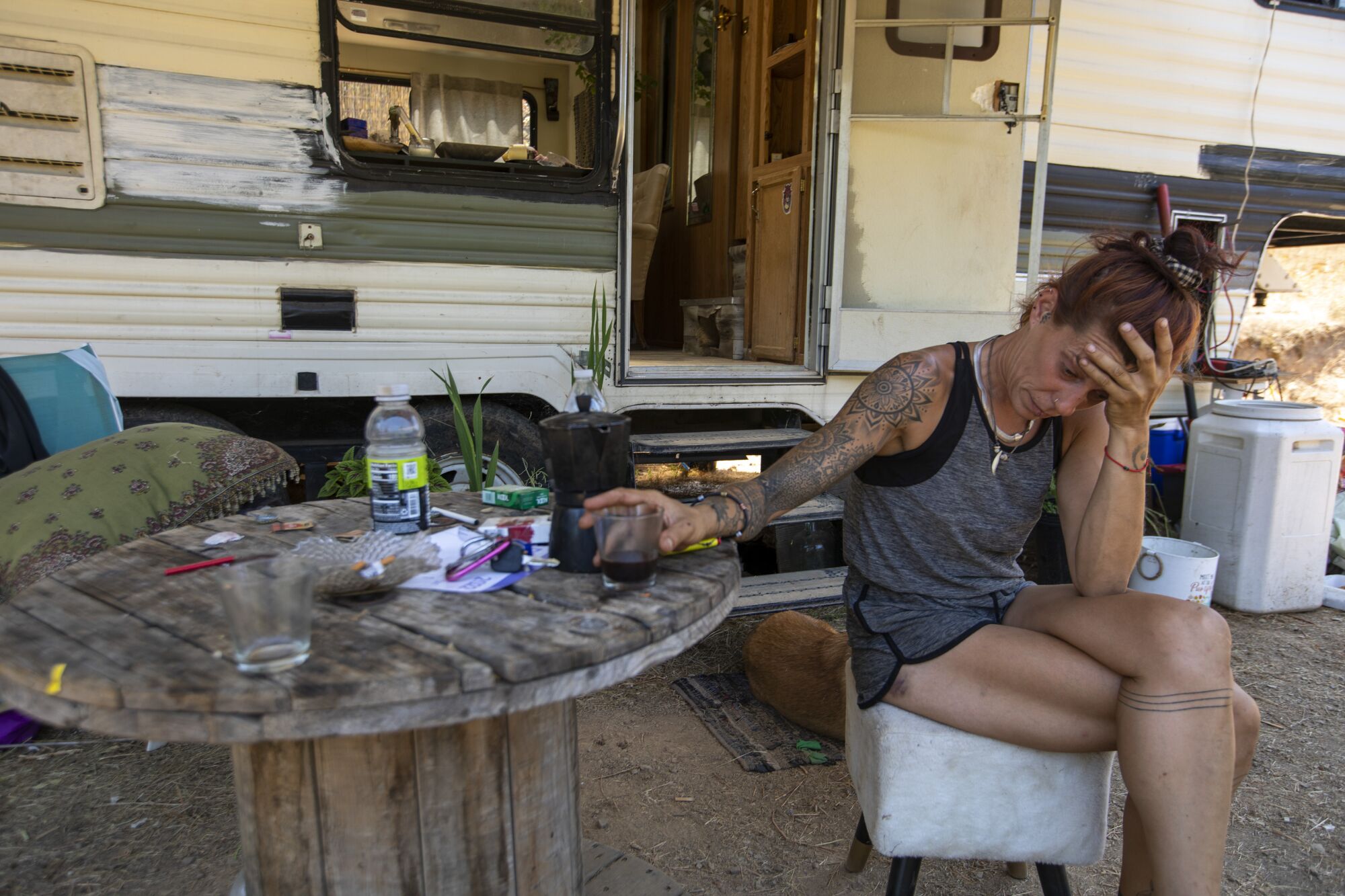 Sabrina, a cannabis worker, sits with a cup of coffee outside her trailer.