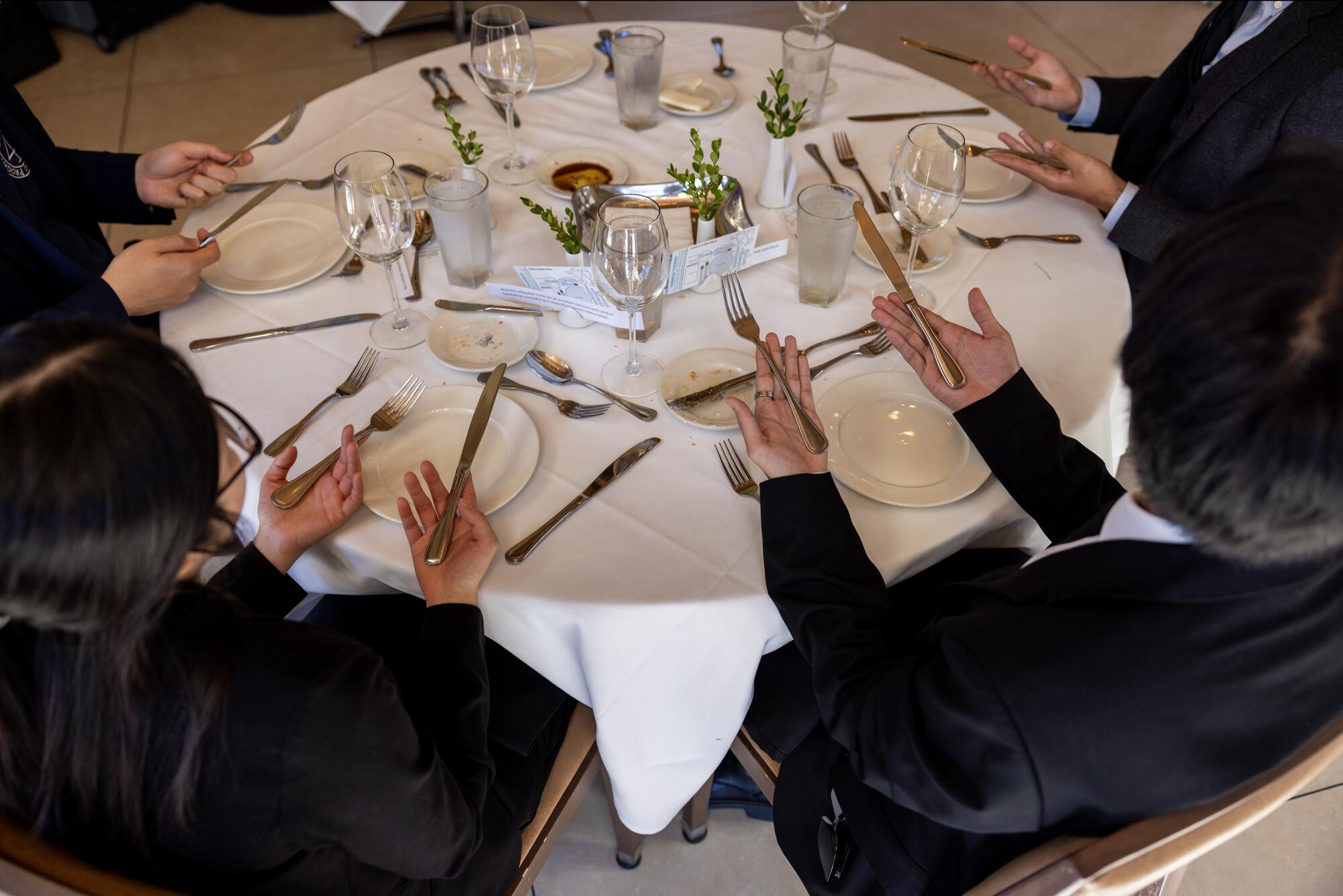 People sitting around a table with utensils in their hands