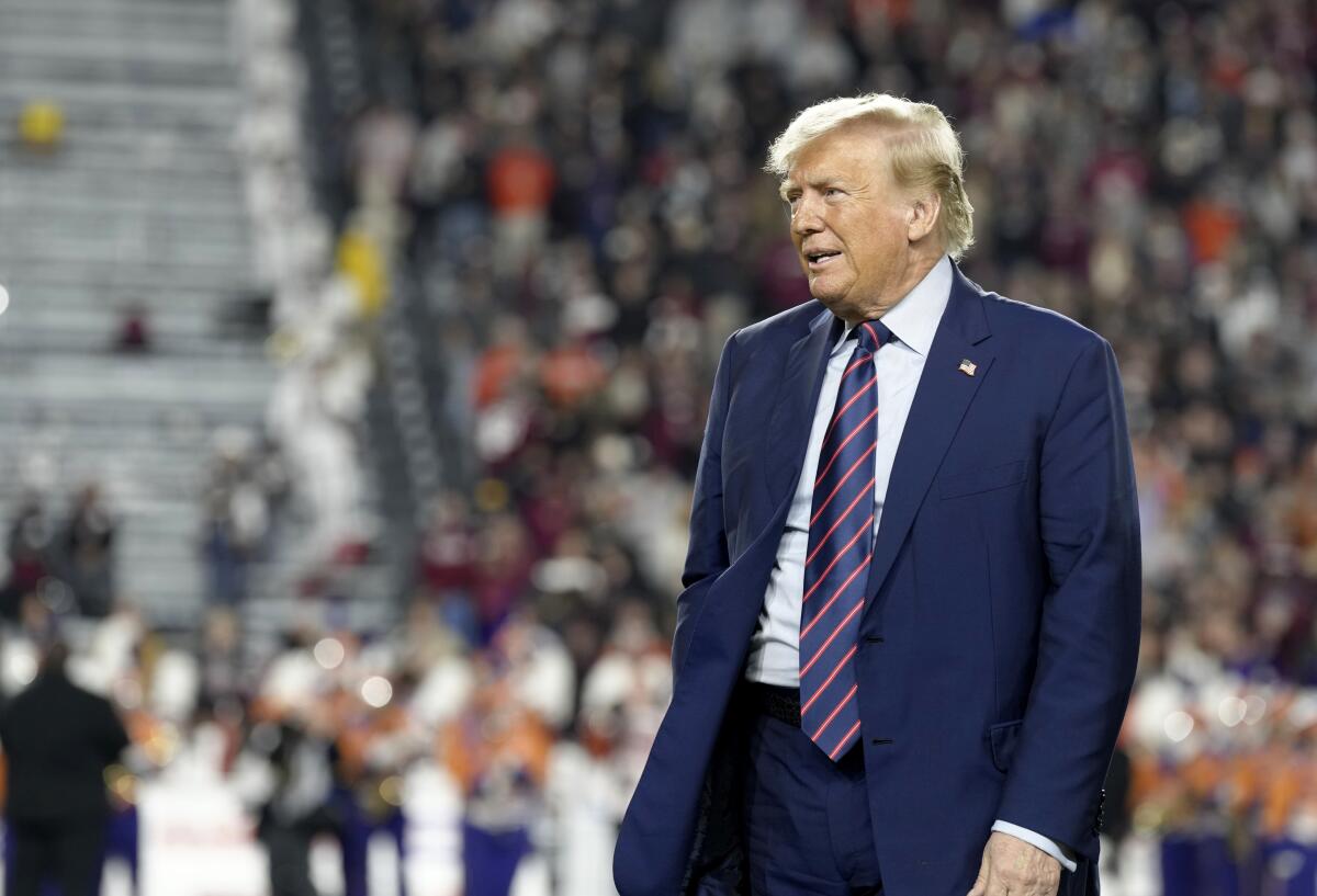 Trump stands on a field at a football stadium at night 