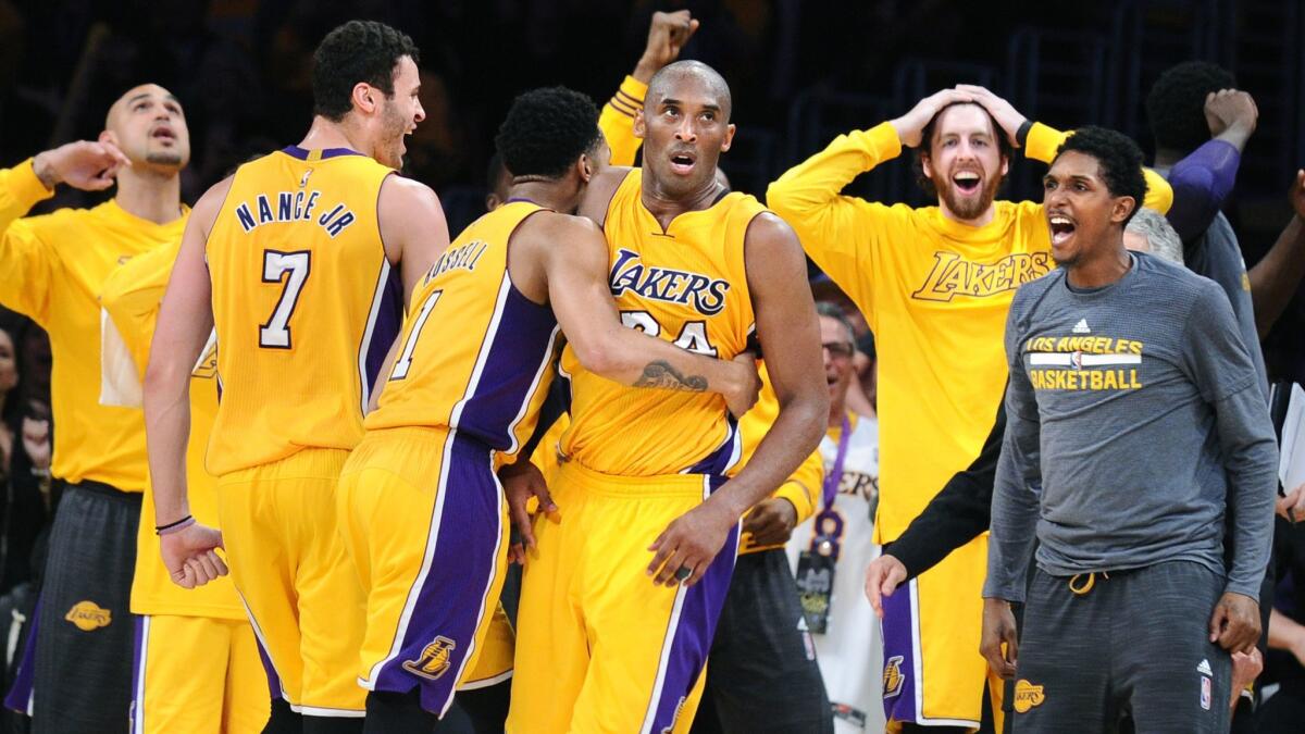 Lakers star Kobe Bryant is mobbed by teammates after scoring 60 points in the final game of his career, a 101-96 victory against the Utah Jazz.