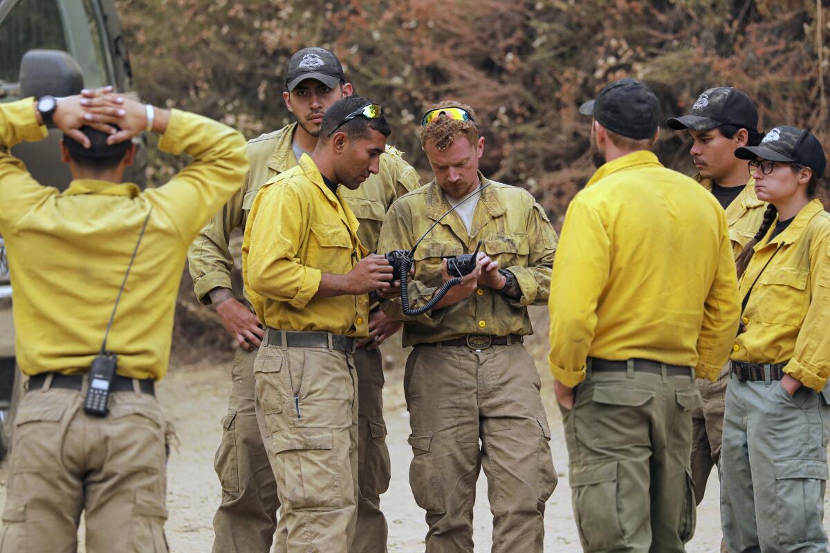 Firefighters huddle to plan their attack on the Bobcat fire in the San Gabriel Mountains on Tuesday.