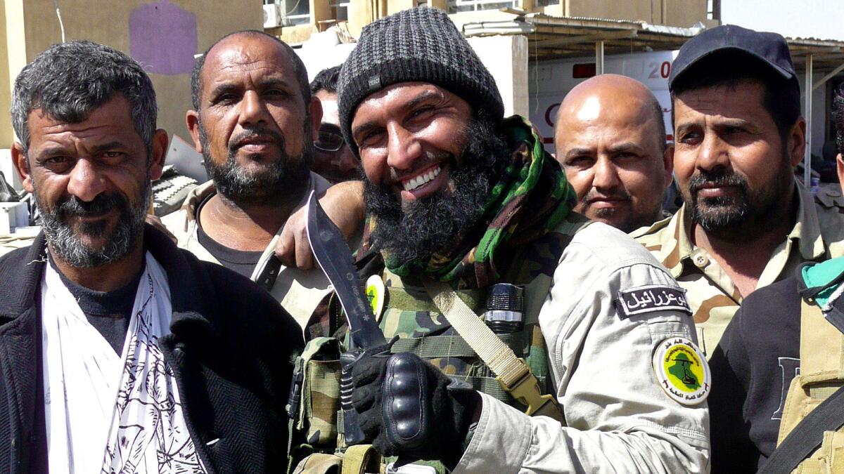 Abu Azrael, center, a hero among Shiite militiamen, poses with fighters near the northern Iraqi city of Tikrit on March 14, 2015.