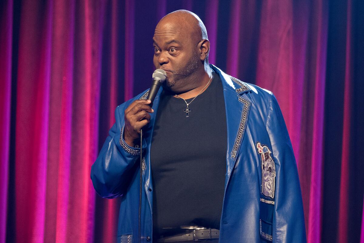Stand-up comedian Lavell Crawford holds a microphone to his mouth.