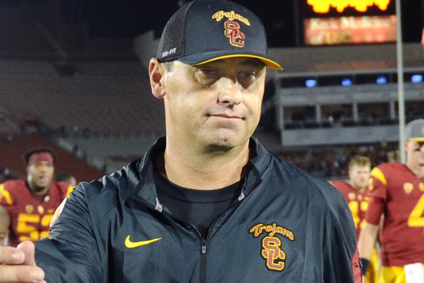 USC head coach Steve Sarkisian, left, walks off the field after the Trojans' loss to Washington in October.