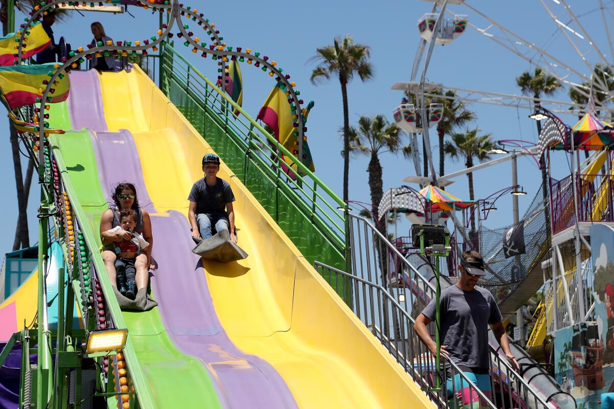 A parent and her children go down the Super Slide during Pier Plaza Festival on Saturday.
