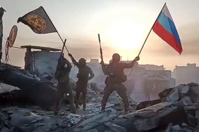 FILE - In this image taken from video and released on Saturday, May 20, 2023, by the press service of Yevgeny Prigozhin, head of the Wagner private military contractor, his forces wave Russian and Wagner flags atop a damaged building in Bakhmut, Ukraine. Some convicts recruited by Wagner to fight in in Ukraine are coming home to Russia and committing new crimes. That has raised fears in communities where the now-freed convicts are returning, and reports of killings, robberies and sexual assaults by some of them are emerging in Russian media. (Prigozhin Press Service via AP, File)