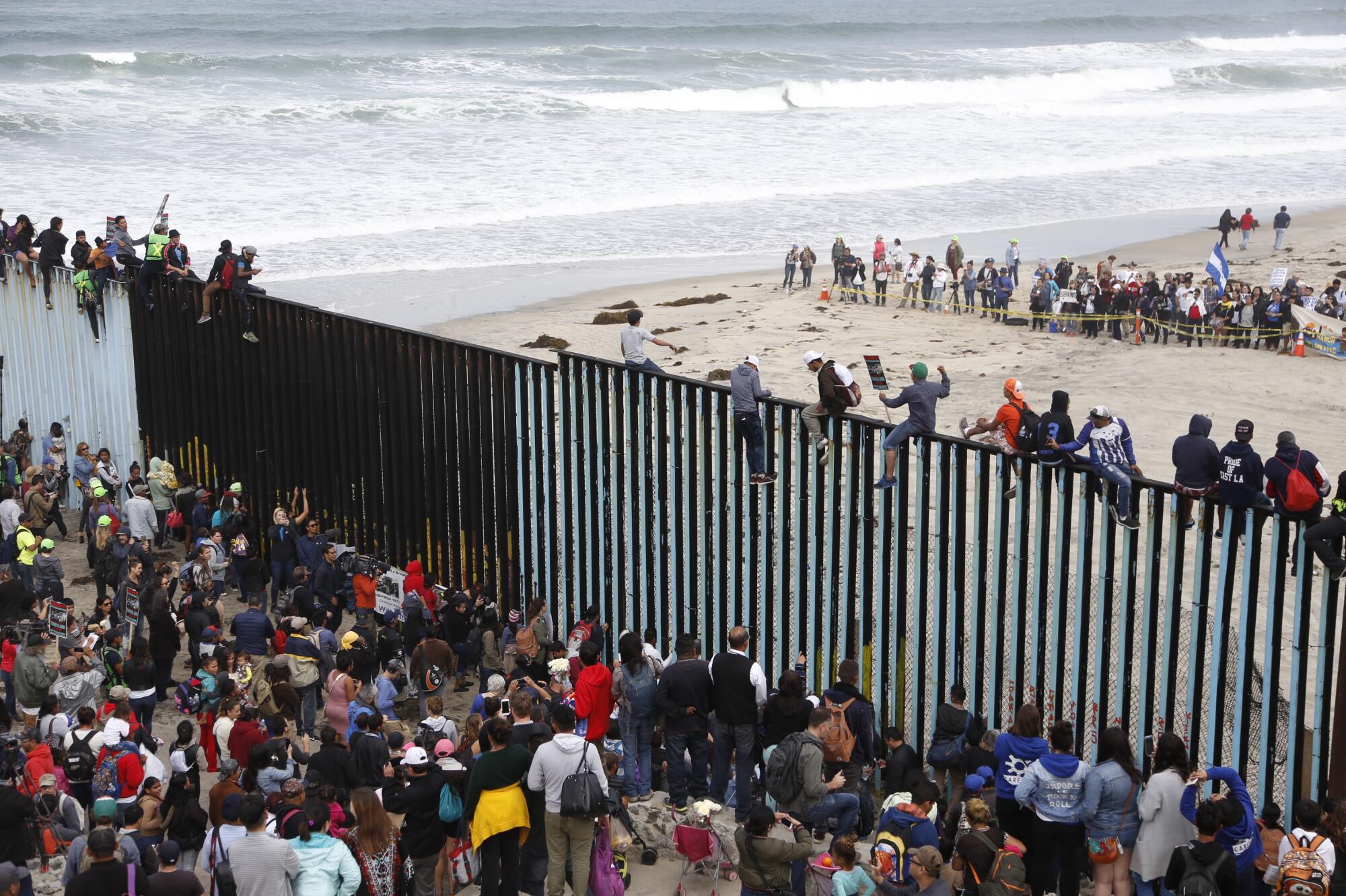 Algunos migrantes celebran su llegada subiéndose a la valla fronteriza entre Estados Unidos y México
