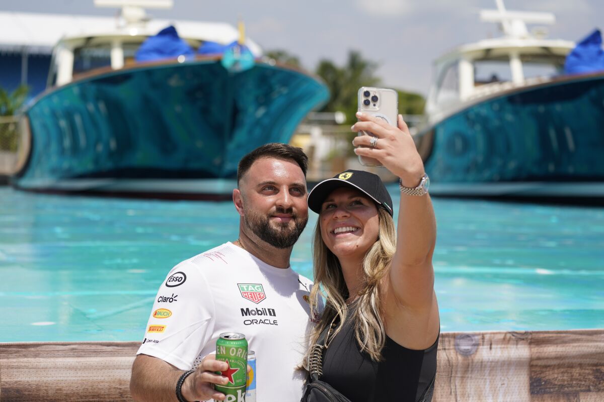 Marc and Isabella pose for a selfie at the man-made marina and beach club during the Formula One Miami Grand Prix auto race at Miami International Autodrome, Friday, May 6, 2022, in Miami Gardens, Fla. (AP Photo/Darron Cummings)