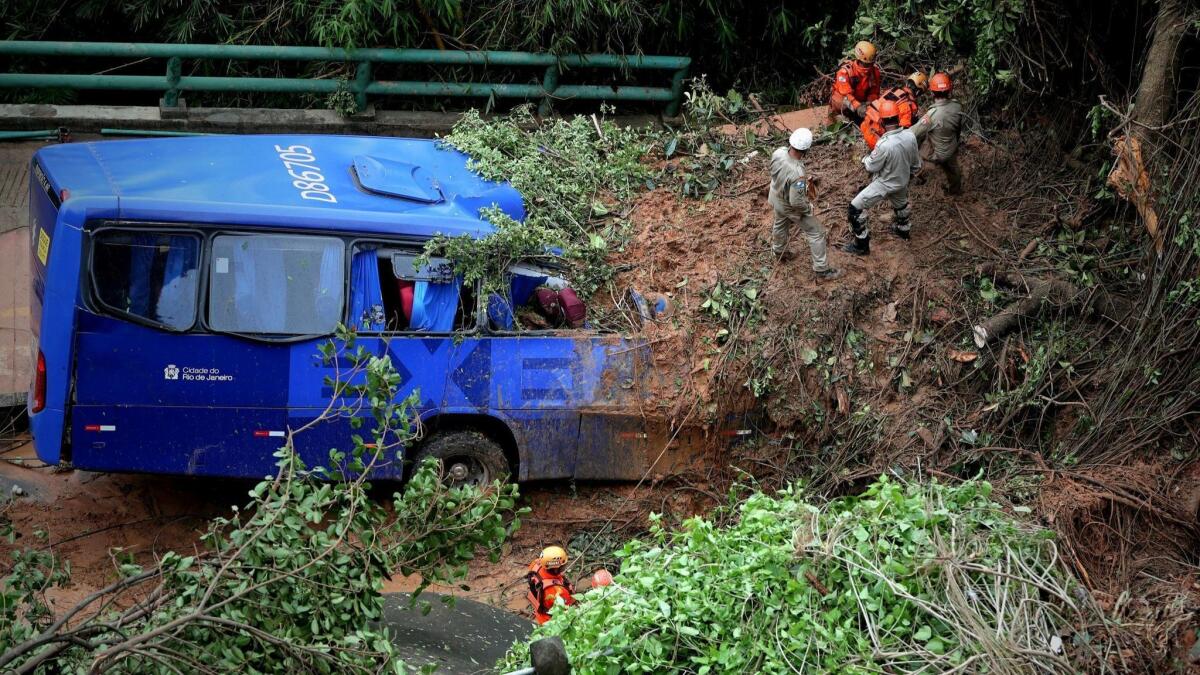 Emergency teams work to extricate a bus buried by a landslide Thursday after overnight storms in Rio de Janeiro.