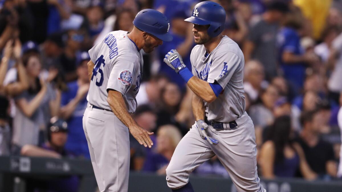 Chris Taylor, right, is congratulated by Dodgers third base coach Chris Woodward after hitting a home run against the Colorado Rockies at Denver on Saturday.