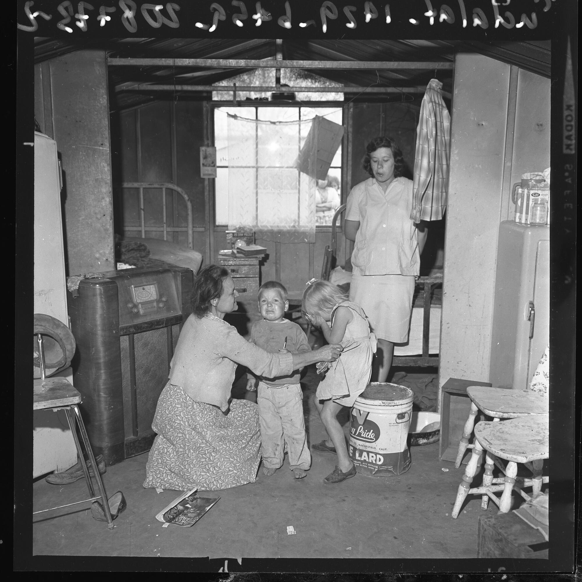 A family sits in one of two metal cabins that were built for migrant farmworkers in the 1930s