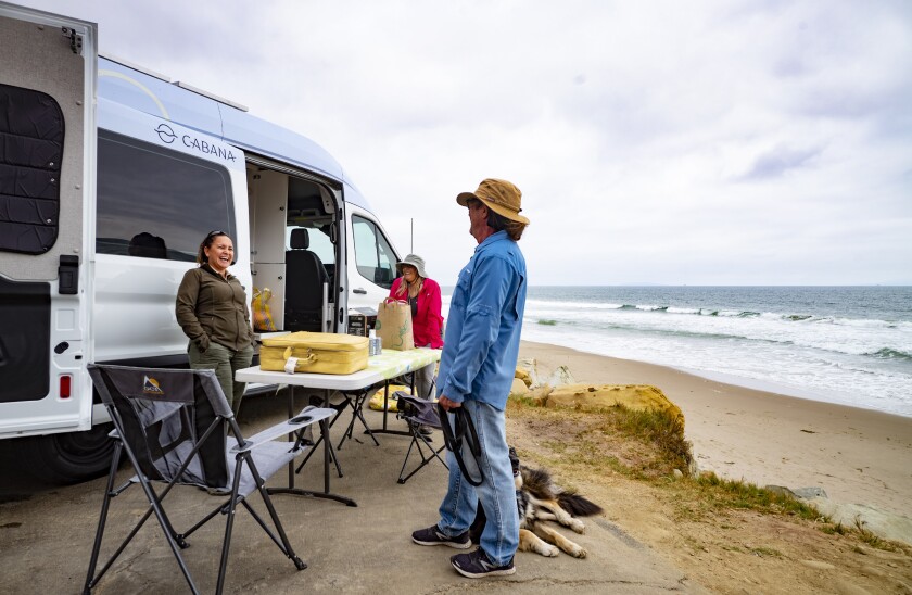 A ranger talks with a man next to a van on the beach