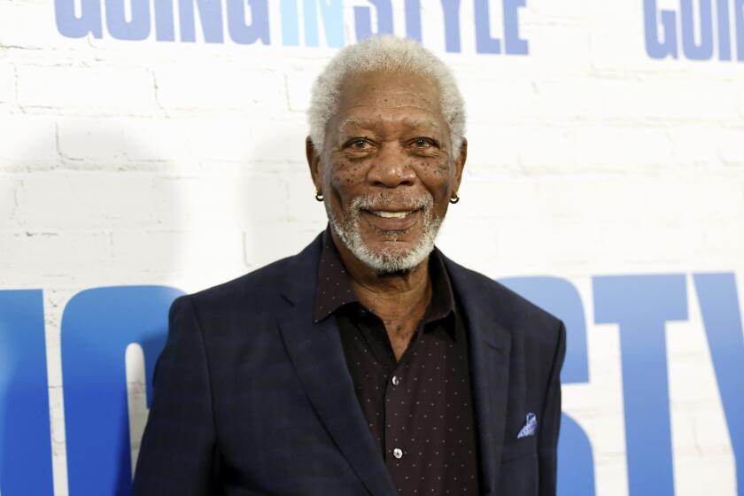 Morgan Freeman smiles in a dark suit against a white background