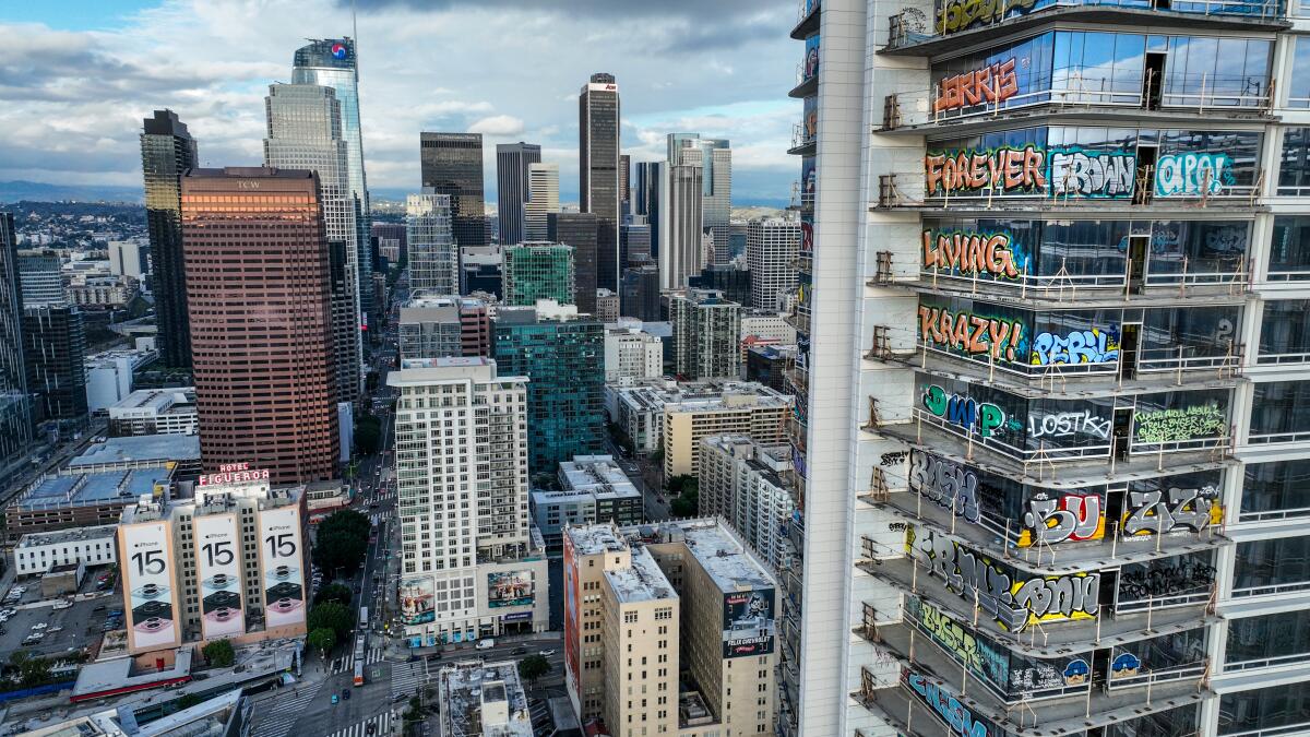 A view of L.A.'s downtown shows a tall tower, at right, with each floor covered in colorful graffiti.