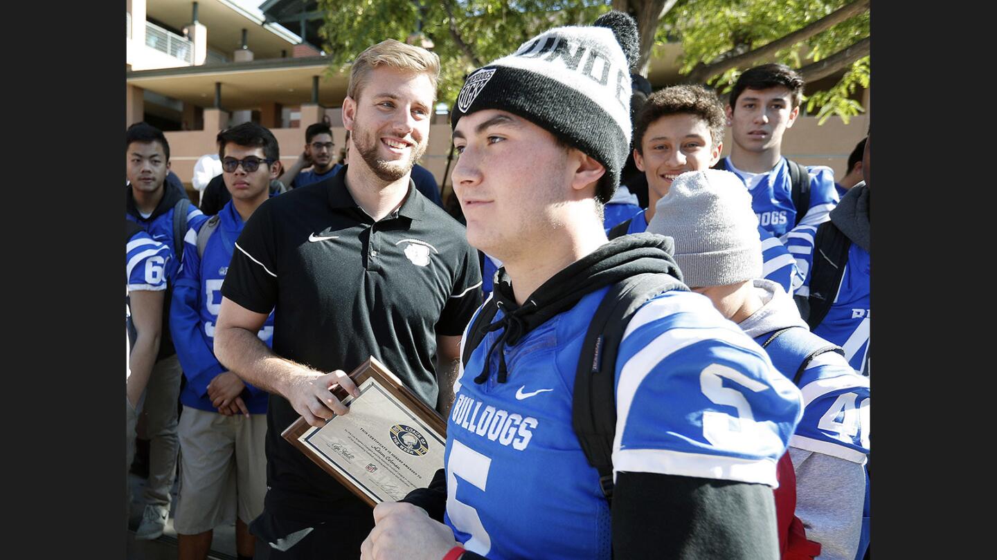 Burbank Football Coach Adam Colman walks with his plaque after the ceremony as football player Blake Quinteros crosses in front of him at Burbank High School on Thursday, November 9, 2017. Coach Colman was recognized as a 2017 Chargers Coach of the Week by the Los Angeles Chargers for his team's recent victory over Crescenta Valley.