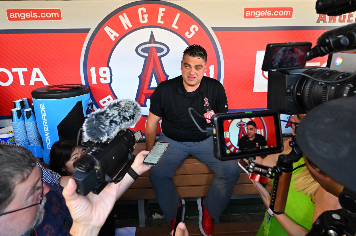 Angels general manager Perry Minasian speaks to the media in the dugout before a game.