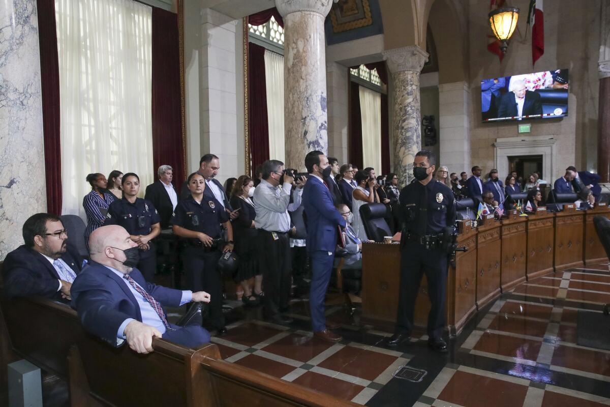 People gathered in City Hall listen to Councilmember Mike Bonin, shown on a screen.