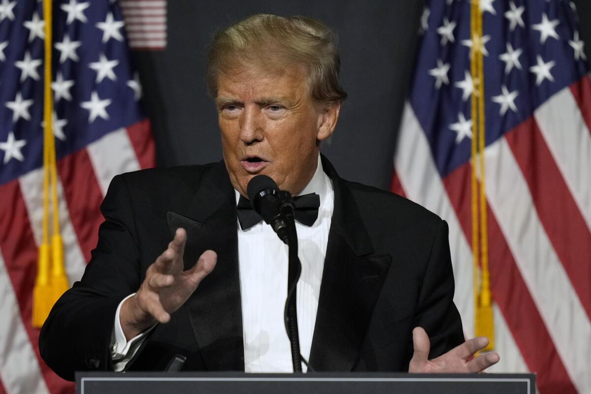 Former President Trump speaking at a microphone in a tuxedo