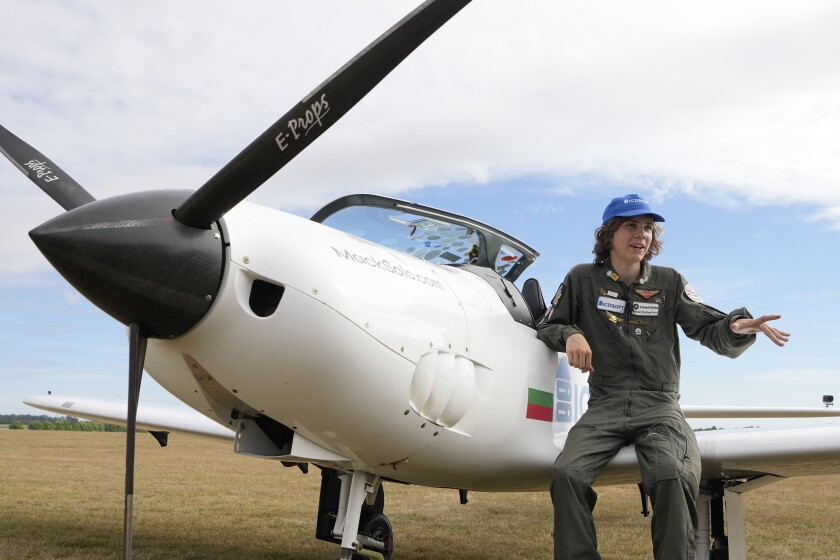 Teen pilot stands next to plane