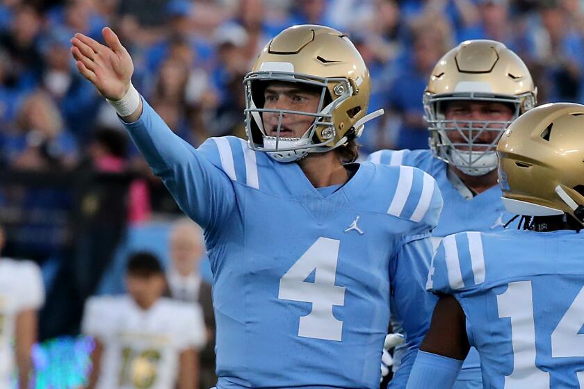 UCLA quarterback Ethan Garbers signals a first down after scrambling in front of fans at the Rose Bowl