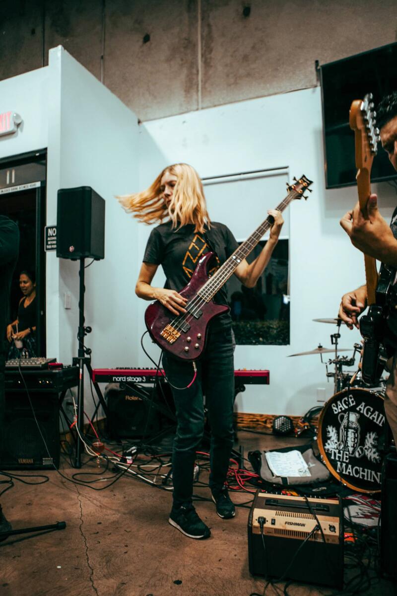 A woman playing bass guitar, her hair flying