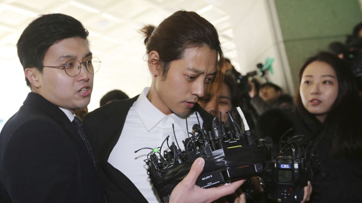 In this March 14, 2019, photo, K-pop singer Jung Joon-young, center, arrives at the Seoul Metropolitan Police Agency in Seoul, South Korea.