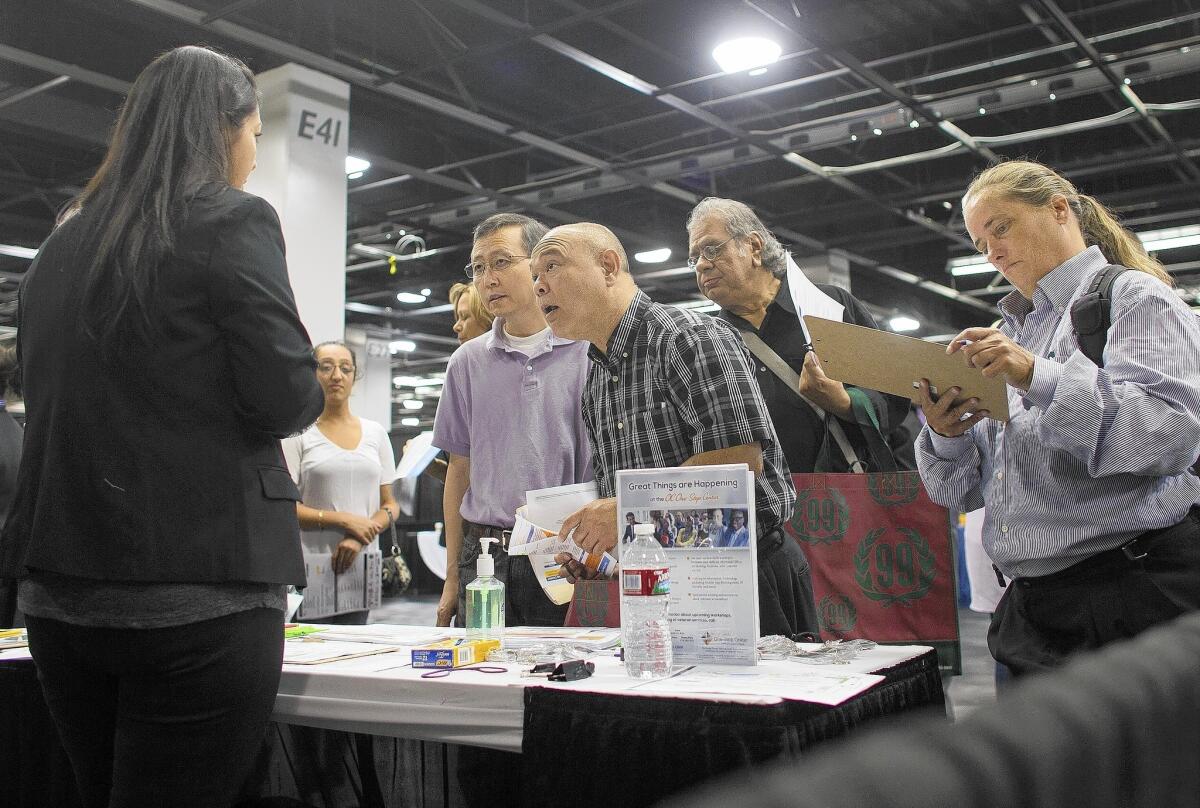 Stella Portillo, left, of Orange County One-Stop Center, talks with job seekers at the Sixth Annual Anaheim/OC Job Fair at the Anaheim Convention Center.