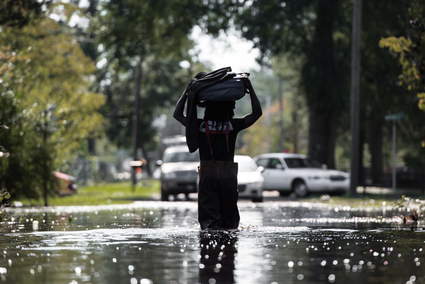A man carries personal items through a flooded street caused by remnants of Hurricane Matthew on Oct. 11, 2016 in Fair Bluff, North Carolina.